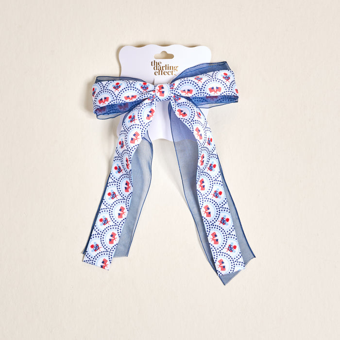 The Darling Effectβs All-American Darling Lovely Layered Hair Bow features stars and flags on white, adding patriotic flair to any hairstyle.