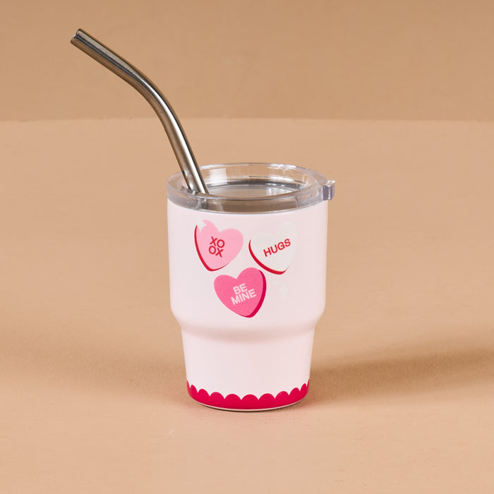 The Darling Effect’s Candy Hearts 2 oz Tiny Tumbler features a white design with pink and red heart phrases like “XO,” “Hugs,” and “Be Mine,” plus a silver metal straw—an adorable touch for your mini tumbler collection.
