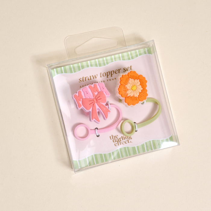 The Darling Effect Made for Mama Straw Topper Set includes two leak-resistant silicone toppers: one pink with "Mama" and a bow, one orange flower. Perfect drinkware accessories packaged in clear plastic for mess-free sipping.