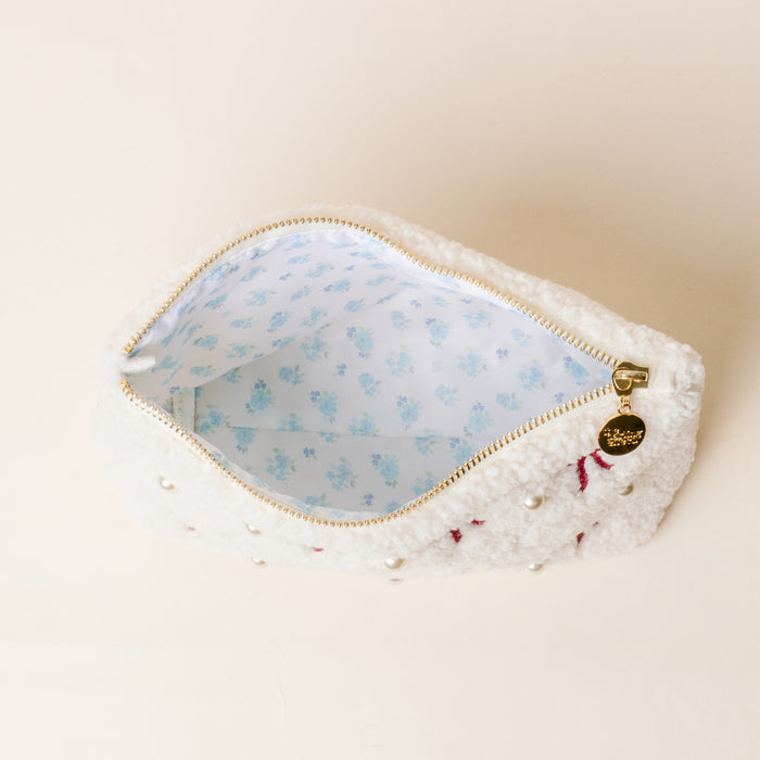 The Darling Effectβs Pi Beta Phi Bows & Pearls Teddy Pouch features white sherpa, pearl and pink embroidered bows, a light blue floral lining, and a gold zipper with charmβperfect as a sorority gift.