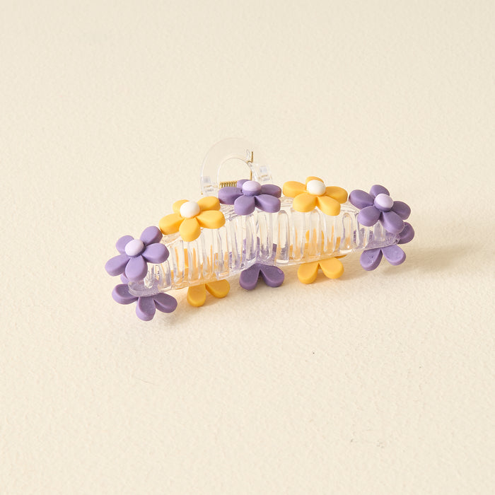 The Darling Effectβs Purple Yellow Game Day Daisy Claw Clip is a clear plastic hair accessory with yellow and purple daisiesβideal for showing school spirit or adding flair to your Game Day look.
