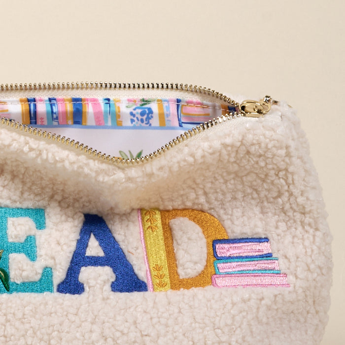 The Darling Effectโs Read Teddy Pouch is a cream sherpa bag with "READ" and books embroidered in colorful threadโperfect for organizing essentials or storing your favorite reads in cute, teddy-inspired style.