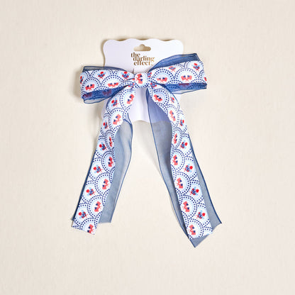 The Darling Effect’s All-American Darling Lovely Layered Hair Bow features stars and flags on white, adding patriotic flair to any hairstyle.