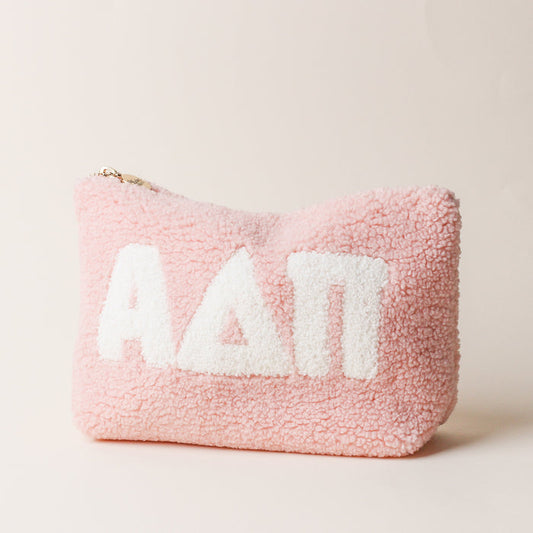 The Darling Effect’s Alpha Delta Pi Blush Teddy Letter Pouch is a soft, fuzzy pink zippered pouch with bold white Greek letters—ideal as a cute teddy pouch or chic carry-on accessory.