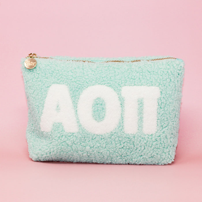 The Darling Effect Alpha Omicron Pi Aqua Teddy Letter Pouch features white sherpa letters, a gold zipper with a charm, and is perfect as a cute sorority or teddy pouch.