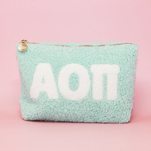 The Darling Effect Alpha Omicron Pi Aqua Teddy Letter Pouch features white sherpa letters, a gold zipper with a charm, and is perfect as a cute sorority or teddy pouch.