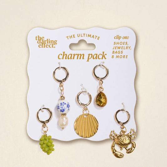 The Darling Effect’s Amalfi Coast The Ultimate Charm Pack includes five gold clip-on charms—green grapes, blue-and-white bead with pearl, gold shell, yellow teardrop gem, and gold crab—perfect for Scrunchie Charm Sets or Make a Statement Necklaces.