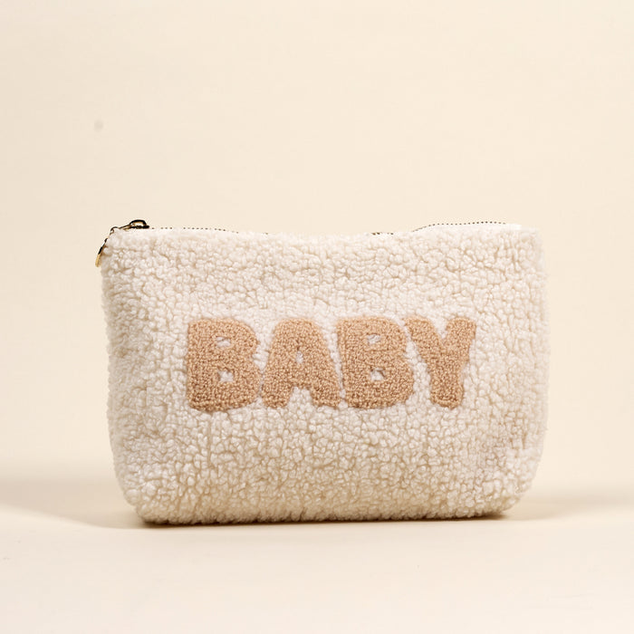 The Darling Effect's Baby Teddy Pouch is a soft, white sherpa zippered pouch featuring "BABY" in large beige letters on the front, set against a neutral backdrop.