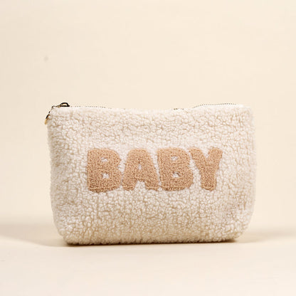 The Darling Effect's Baby Teddy Pouch is a soft, white sherpa zippered pouch featuring "BABY" in large beige letters on the front, set against a neutral backdrop.