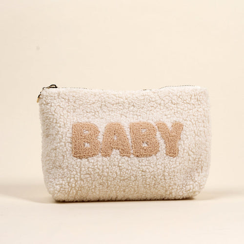 The Darling Effect's Baby Teddy Pouch is a soft, white sherpa zippered pouch featuring "BABY" in large beige letters on the front, set against a neutral backdrop.