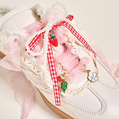 The Darling Effect’s Berry Fresh Dazzle Shoe Charm Pack features playful sneaker charms shaped like a strawberry, leaf, pearl, and white flower—perfect for adorning white sneakers with pink laces and gingham ribbon accents.
