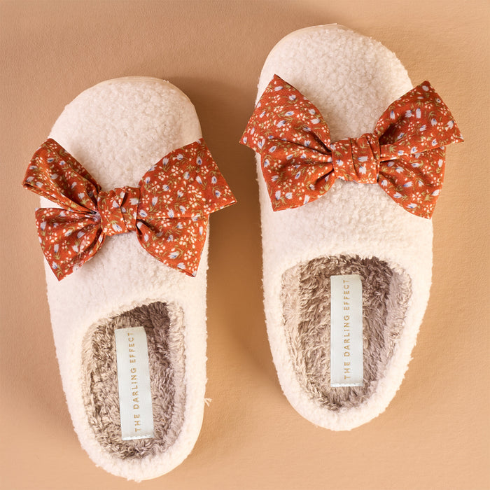 Betty Bow Fall Flora Fuzzy Slippers by The Darling Effect are fluffy white slippers decorated with orange floral bows.