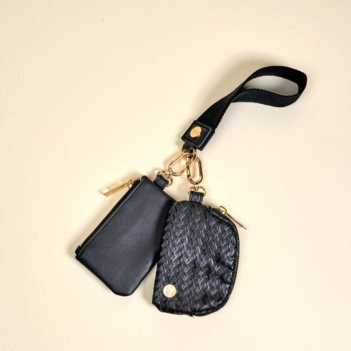The Darling Effect's Black Dynamic Duo Pouch Luxe Wristlet features two black zippered pouches—one smooth leather, one woven—on a luxe wristlet with gold hardware for chic, hands-free style.