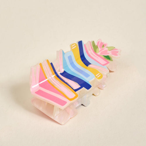 The Book Nook Shape Up Claw Clip by The Darling Effect showcases pastel pink, yellow, blue, and navy stripes in a floral design—perfect as a cute hair accessory to brighten up your favorite hairstyle.