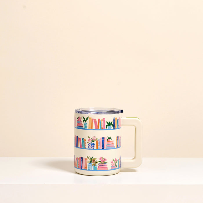The Darling Effect’s Book Shelfie 14 oz Insulated Mug features a white handle and colorful book and plant illustrations on beige shelves. Its insulation keeps drinks hot or cold while you sip your favorite beverage.
