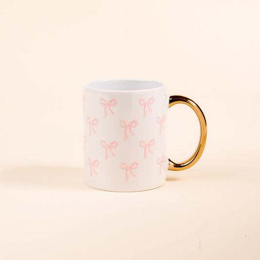 The Darling Effect’s Bows Pink 11 oz Cozy Cute Ceramic Mug features a golden handle and a repeating pink bow pattern—ideal for sipping your favorite coffee or tea.