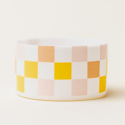 The Darling Effect Check Peach Tumbler Silicone Boot is a white cylindrical tumbler with yellow, pink, and light orange checkerboard squares and a silicone boot for extra protection.