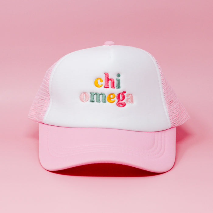 The Darling Effect Chi Omega Pink Trucker Hat features colorful "chi omega" embroidery on the front, shown against a solid pink background.