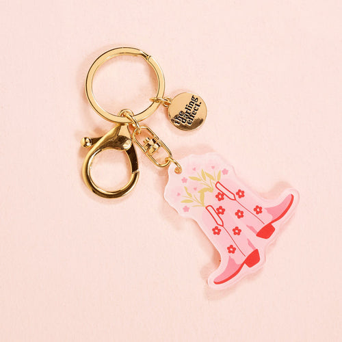 The Cowgirl Boots Acrylic Keychain by the-darling-effect features a gold keychain with a round “Darling Effect” charm and a pink floral cowboy boots acrylic charm—making it the cutest pick for stylish keychain accessories.