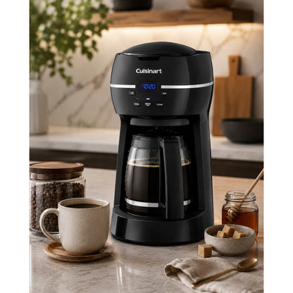 Catalog scene of black Cuisinart DCC-1500FR coffee maker with filled glass carafe, coffee cup, beans, honey, and sugar on a kitchen counter.