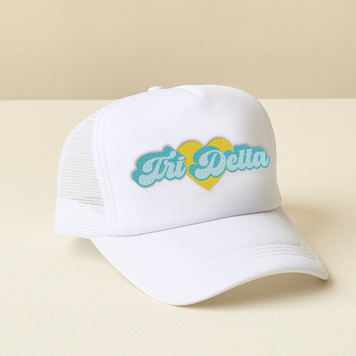 The Darling Effect Delta Delta Delta White Trucker Hat features "Tri Delta" in blue script above a yellow heart on white mesh—ideal as an embroidered sorority hat or a thoughtful sisterhood gift.