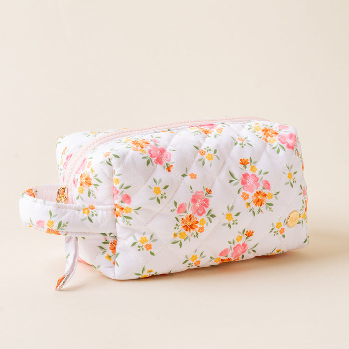 The-darling-effect's Endless Daydream Cream Essentials Quilted Cosmetic Pouch features pink and orange flowers on white, a side handle, and a light pink zipper—ideal for carrying your essentials while traveling.