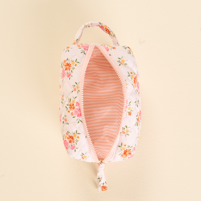 The Endless Daydream Cream Essentials Quilted Cosmetic Pouch by the-darling-effect features a white rectangular design with pink and orange floral patterns, a pink zipper, handle, and a striped interior—perfect for stylish travel makeup storage.