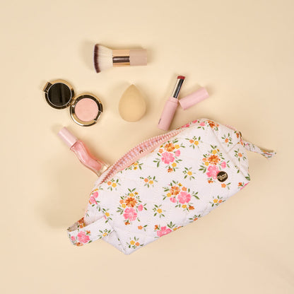 The-darling-effect's Endless Daydream Cream Essentials Quilted Cosmetic Pouch on beige, styled with powder compact, pink lipstick, lip gloss, makeup brush, and blending sponge. Features a wipeable interior for easy cleaning.