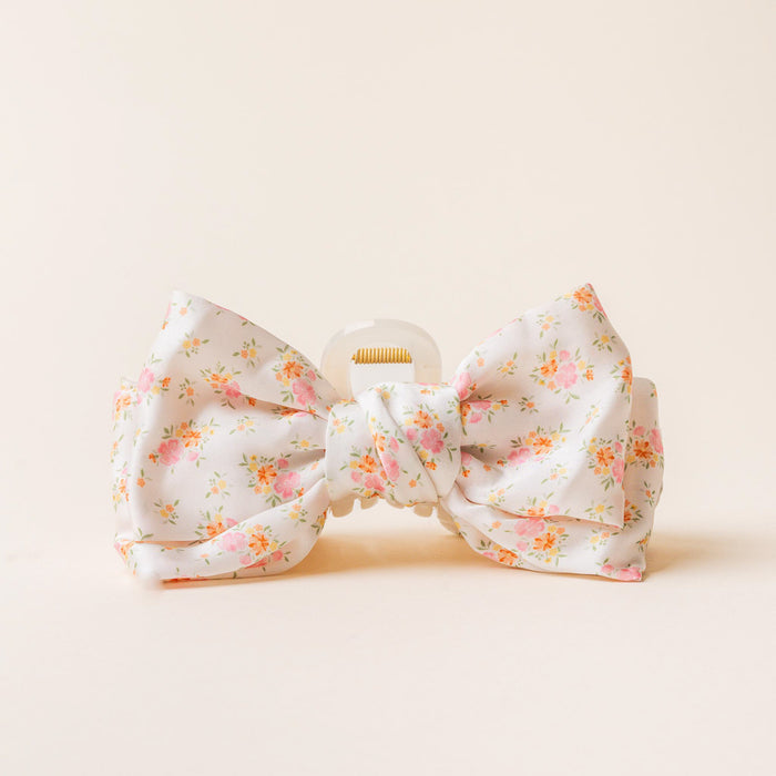 The Endless Daydream Cream Satin Bow Claw Clip by the-darling-effect features a large white satin bow with pink and orange floral details and a knotted center—an elegant accessory for any occasion.