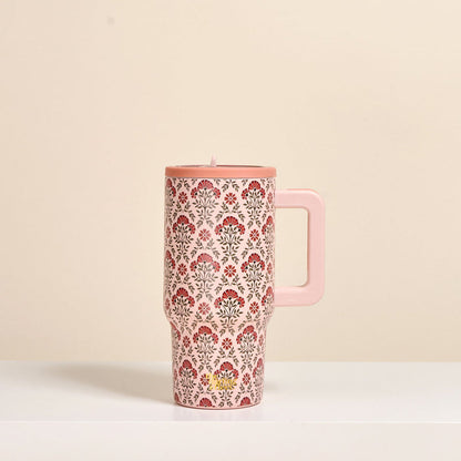 The Darling Effect Everbloom Dusty Rose 20 oz Lifestyle Flip Straw Tumbler, featuring a red and gray floral pattern and handle, sits on a white surface against a beige background. This insulated stainless steel mug keeps drinks perfectly hot or cold.