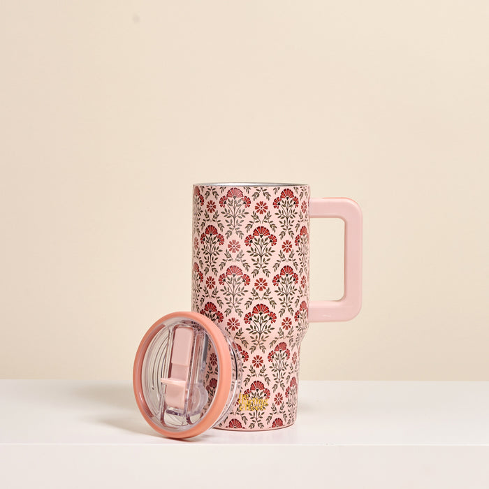 The Darling Effect Everbloom Dusty Rose 20 oz Lifestyle Flip Straw Tumbler, featuring a red and gray floral design, stands upright with its matching lid on a white surface against a beige background.