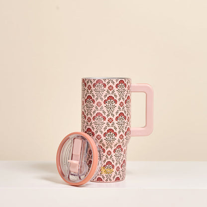 The Darling Effect Everbloom Dusty Rose 20 oz Lifestyle Flip Straw Tumbler, featuring a red and gray floral design, stands upright with its matching lid on a white surface against a beige background.