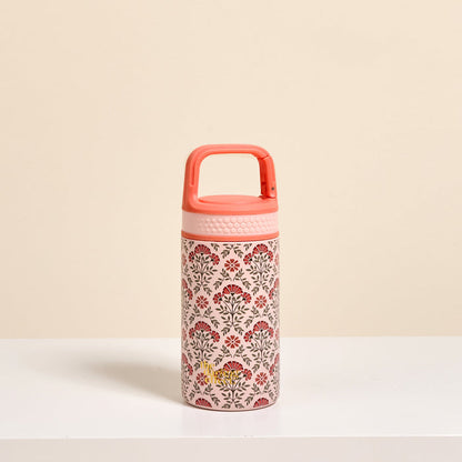 The Darling Effect’s Everbloom Dusty Rose 6 oz Lil' Bitty Bottle, featuring a handle and red-brown floral design, stands on a white surface against a beige background—perfect for stylish hydration wherever you go.