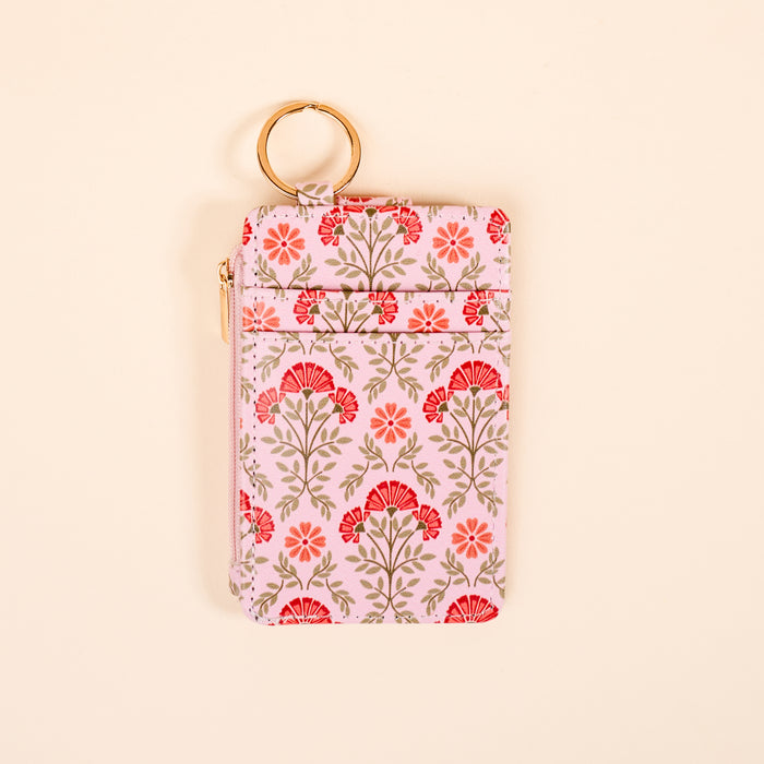 The Darling Effect's Everbloom Dusty Rose Keychain Wallet is a slim, rectangular coin holder with a gold keyring, pink background, red and green floral pattern, zipper closure, and front pocket—perfect for organizing essentials.