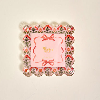 The Everbloom Dusty Rose Square Scalloped Acrylic Picture Frame by The Darling Effect features a decorative tray-like design with floral patterns, pink accents, and modern charm—perfect for displaying treasured memories.