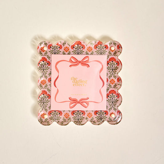The Everbloom Dusty Rose Square Scalloped Acrylic Picture Frame by The Darling Effect features a decorative tray-like design with floral patterns, pink accents, and modern charm—perfect for displaying treasured memories.