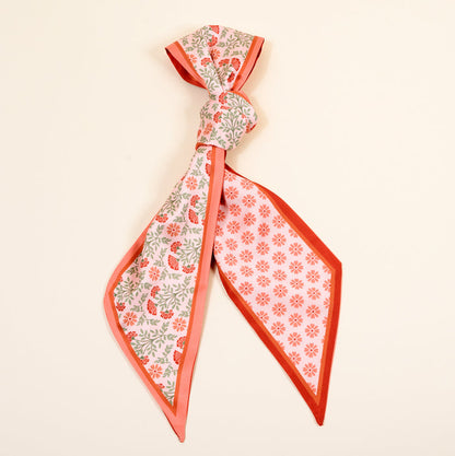 The Darling Effect's Everbloom Dusty Rose Twirl & Tie Scarf Accessory features a pink and red floral pattern on one side, red daisies on the other, and easily ties for boutique charm. Perfect to elevate any outfit.