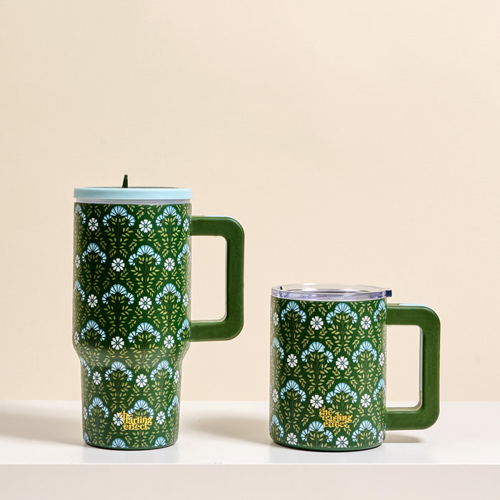 Two Everbloom Forest Green 20 oz Lifestyle Flip Straw Tumblers by The Darling Effect are placed side by side on a white surface against a beige background.