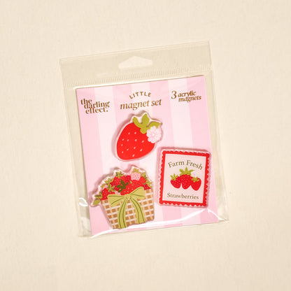 The Darling Effect's Farm Fresh Strawberries Little Magnet Set includes three decorative acrylic fridge magnets with strawberry-themed designs on a pink and white striped background.