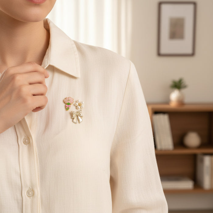 A woman wears The Darling Effect’s Floral Fancy The Pin Pack—a cream blouse finished with a gold brooch adorned with a pink flower bouquet, pearls, and a bow—for an elegant and unique collectible accessory.