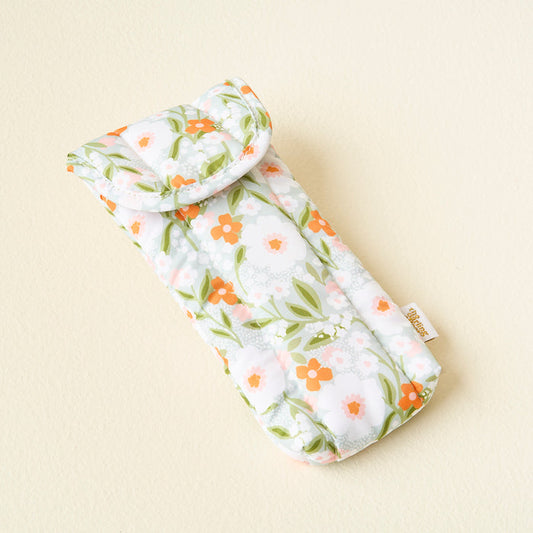 The Darling Effect Floral Haven Sage Sunglasses Case features light blue padding, a floral pattern with white, pink, and orange flowers with green leaves, and a small gold tag on the right side.