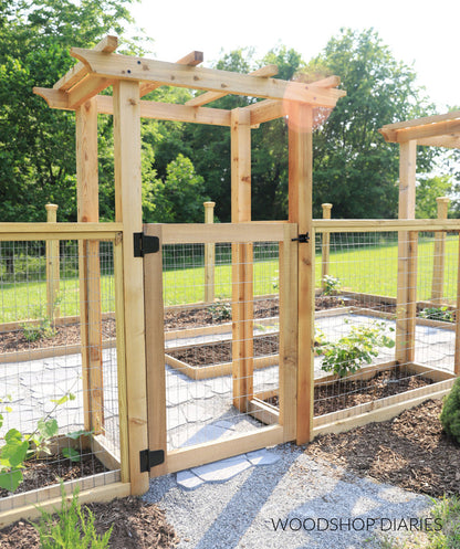 DIY garden arbor with optional gate wood arbor entry with black hardware, wire fencing, and raised vegetable garden beds