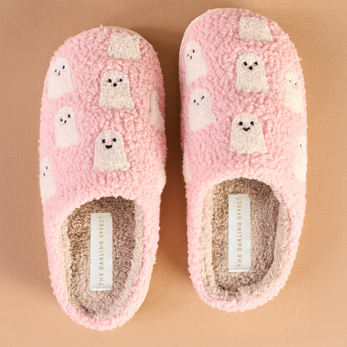The Darling Effect Ghosts Fuzzy Slippers feature pink fuzz, white cartoon ghost designs, and cream insoles with a visible brand label—perfect fall-themed slippers shown side by side on a beige background.
