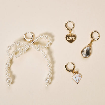 On the left is a gold keyring with a pearl bow charm; on the right are three gold keyrings from The Darling Effect’s Happily Ever After The Ultimate Charm Pack: a heart labeled LOVE, a teardrop gem, and a white diamond shape.