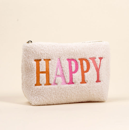 The Darling Effect's Happy Edit Teddy Pouch is a small, white sherpa zippered pouch with "HAPPY" embroidered in orange and pink, shown on a beige background—perfect for your accessory collection of teddy pouches.