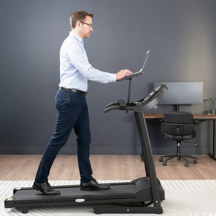 Man using a treadmill desk in an office setting while walking on treadmill.
