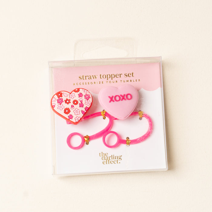 The Darling Effect's Hugs & Kisses Straw Topper Set includes two pink heart-shaped silicone toppers—one with flowers, one with "XOXO." Leak-resistant and ideal for Valentine’s Day, all in signature packaging.