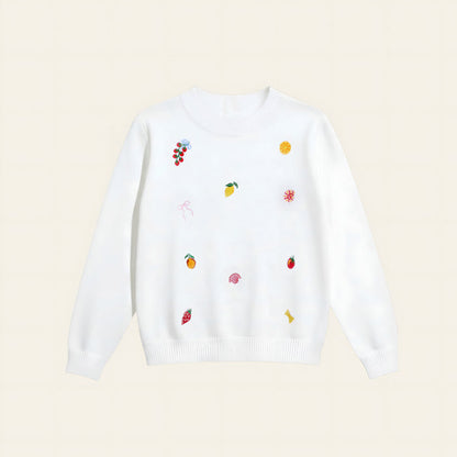 The Darling Effect’s Italian Summer Refined Knit Sweater is a white, tailored knit adorned with playful, colorful embroidered fruit—grapes, lemon slices, strawberries, oranges—and whimsical shapes for a timeless wardrobe update.