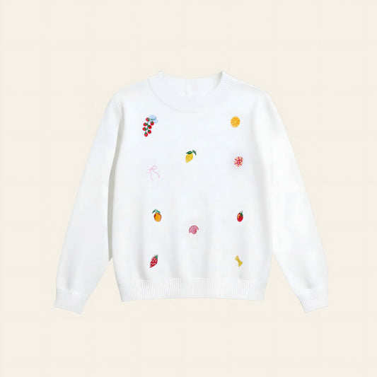 The Darling Effect’s Italian Summer Refined Knit Sweater is a white, tailored knit adorned with playful, colorful embroidered fruit—grapes, lemon slices, strawberries, oranges—and whimsical shapes for a timeless wardrobe update.