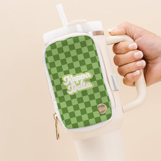 A hand holds a white tumbler with The Darling Effect’s Kappa Delta Tumbler Fanny Pack—a green checkered, water-resistant pouch displaying “Kappa Delta” in bold white script and a gold emblem by the zipper.